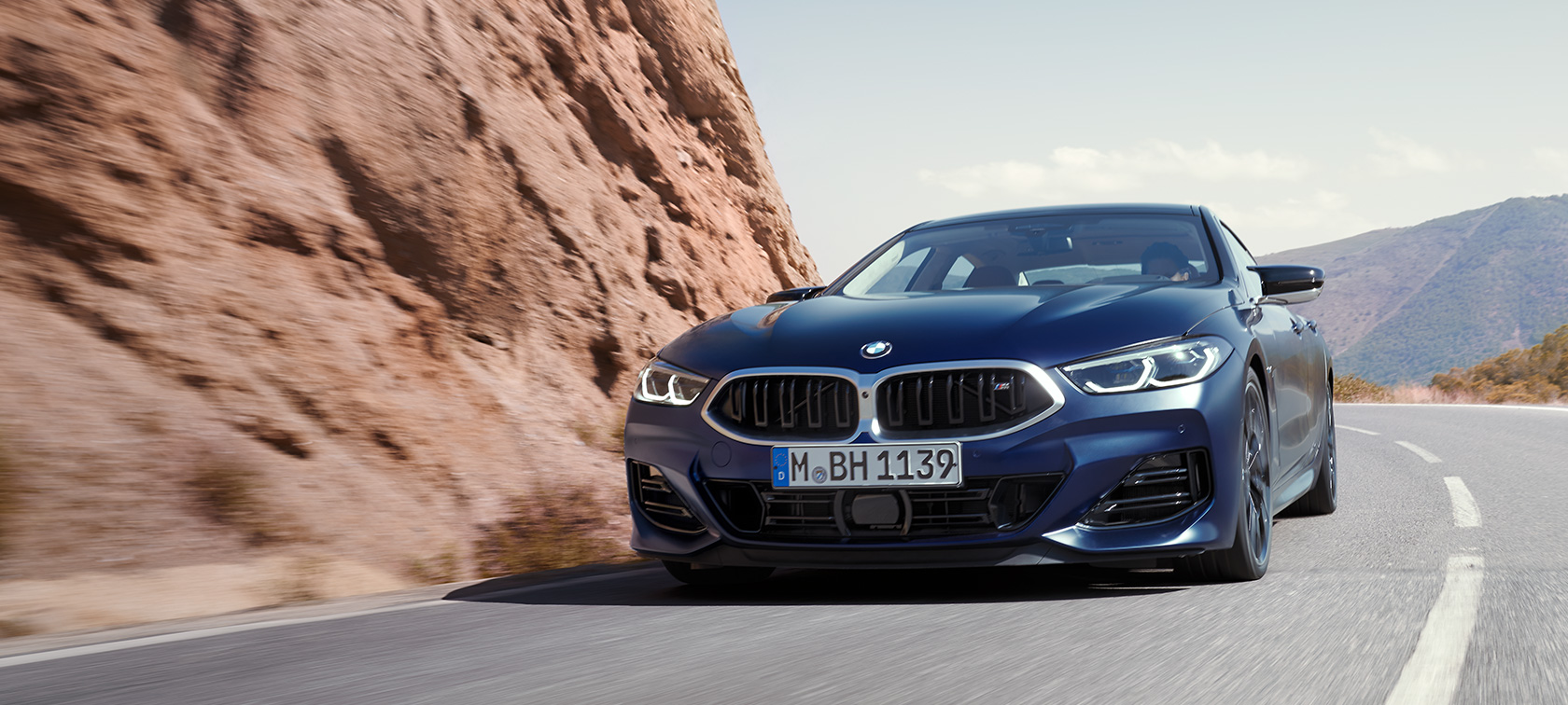 BMW 8. sērijas Gran Coupé G16, LCI, atjaunināts, 2022, BMW Individual metāliska Frozen Tanzanite Blue krāsa, trīs ceturtdaļu priekšpuses skats, braucienā pa kalnu ceļu