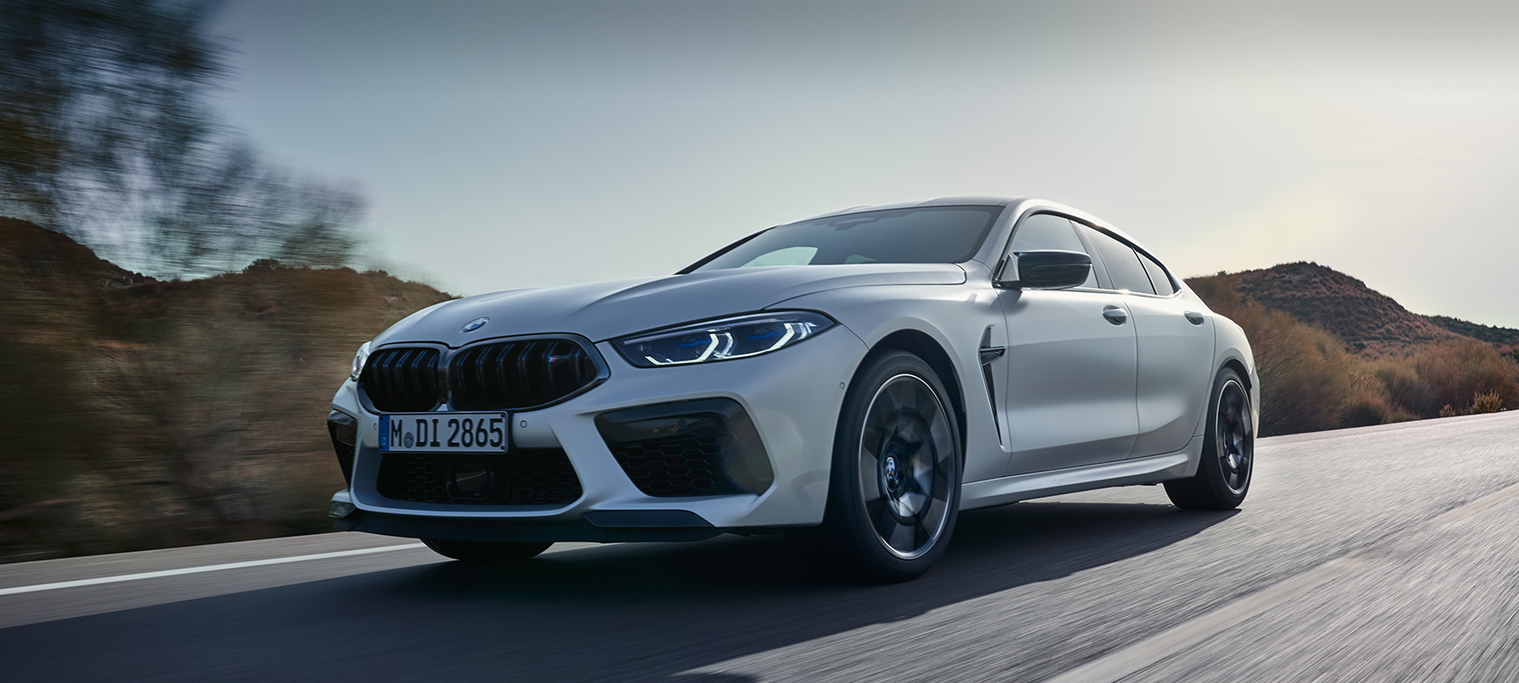 Jaunā BMW M8 Competition Gran Coupé F93, LCI, atjaunināts, 2022, BMW Individual metāliska Frozen Tanzanite Blue krāsa, trīs ceturtdaļu priekšpuses skats, braucienā