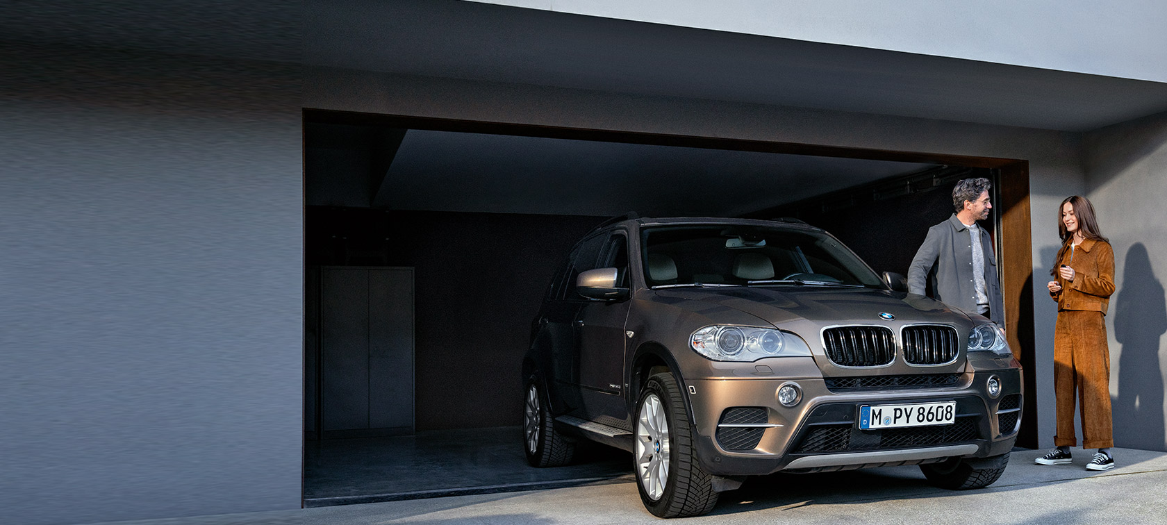 BMW Value Service, vīrietis un sieviete uz garāžas fona ar BMW X5